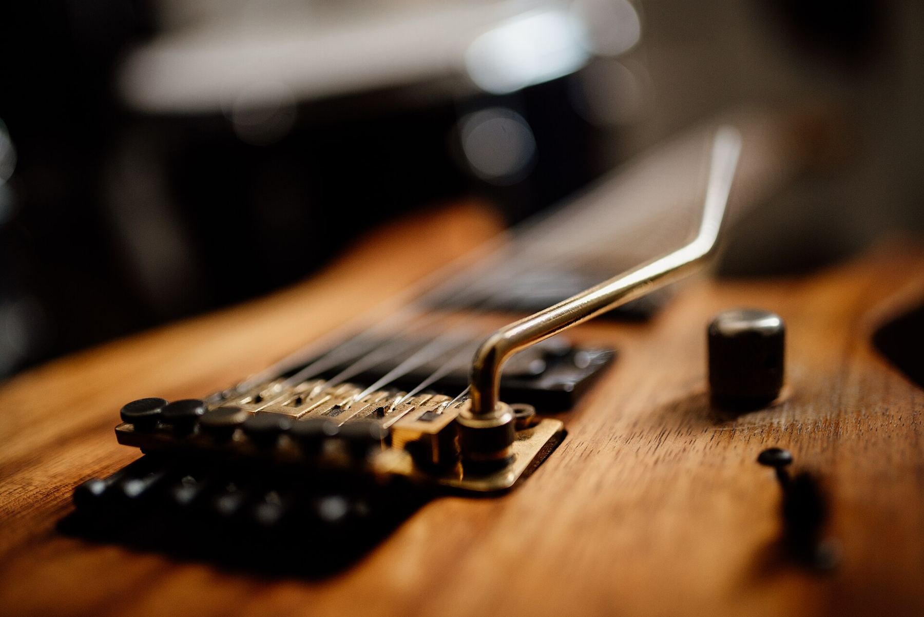 Close-up of an electric guitar bridge and tremolo arm in warm light