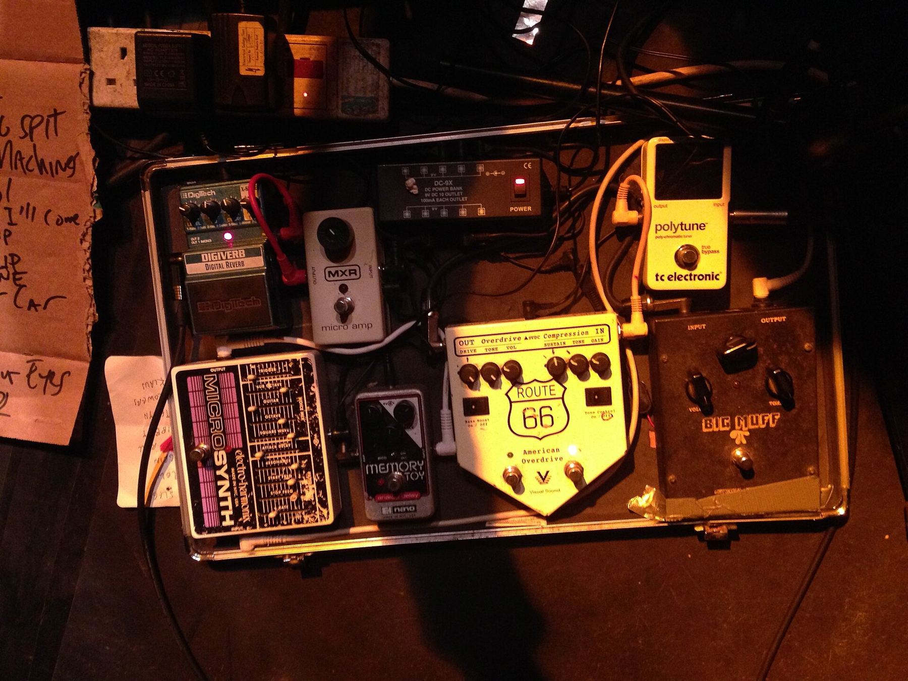 A pedalboard of guitar effects glowing under warm stage light