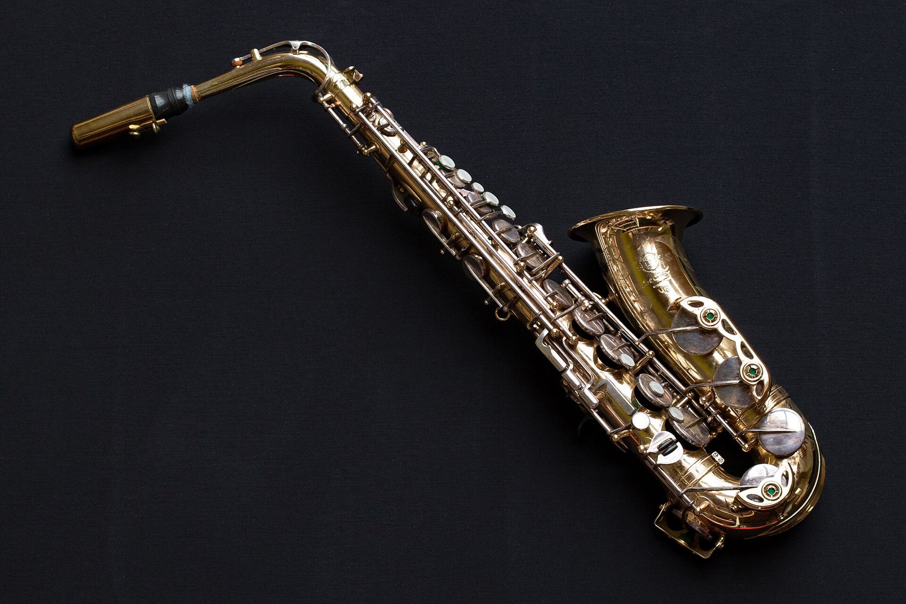 A brass saxophone lying on a dark background