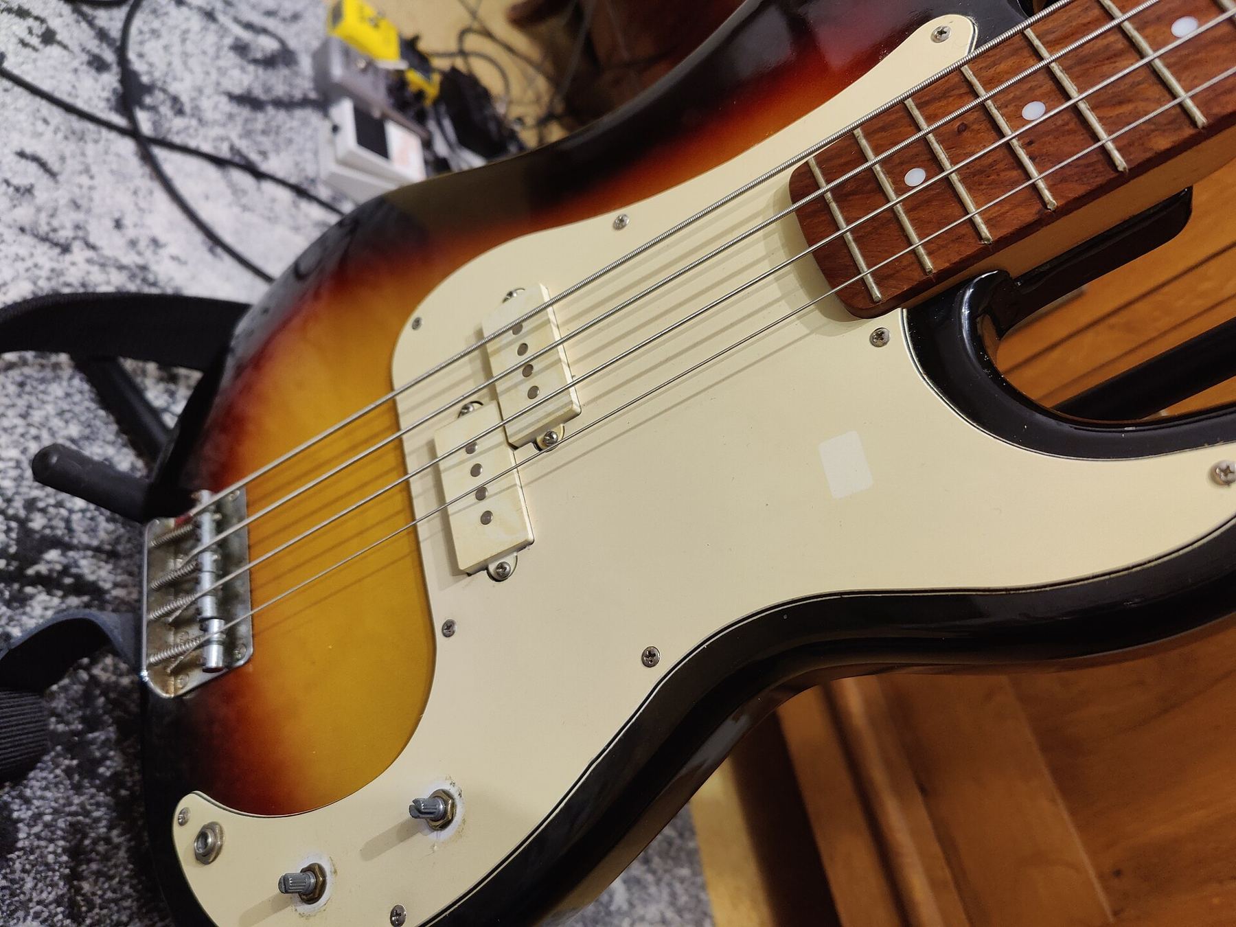 Close-up of a sunburst electric bass with a cream pickguard