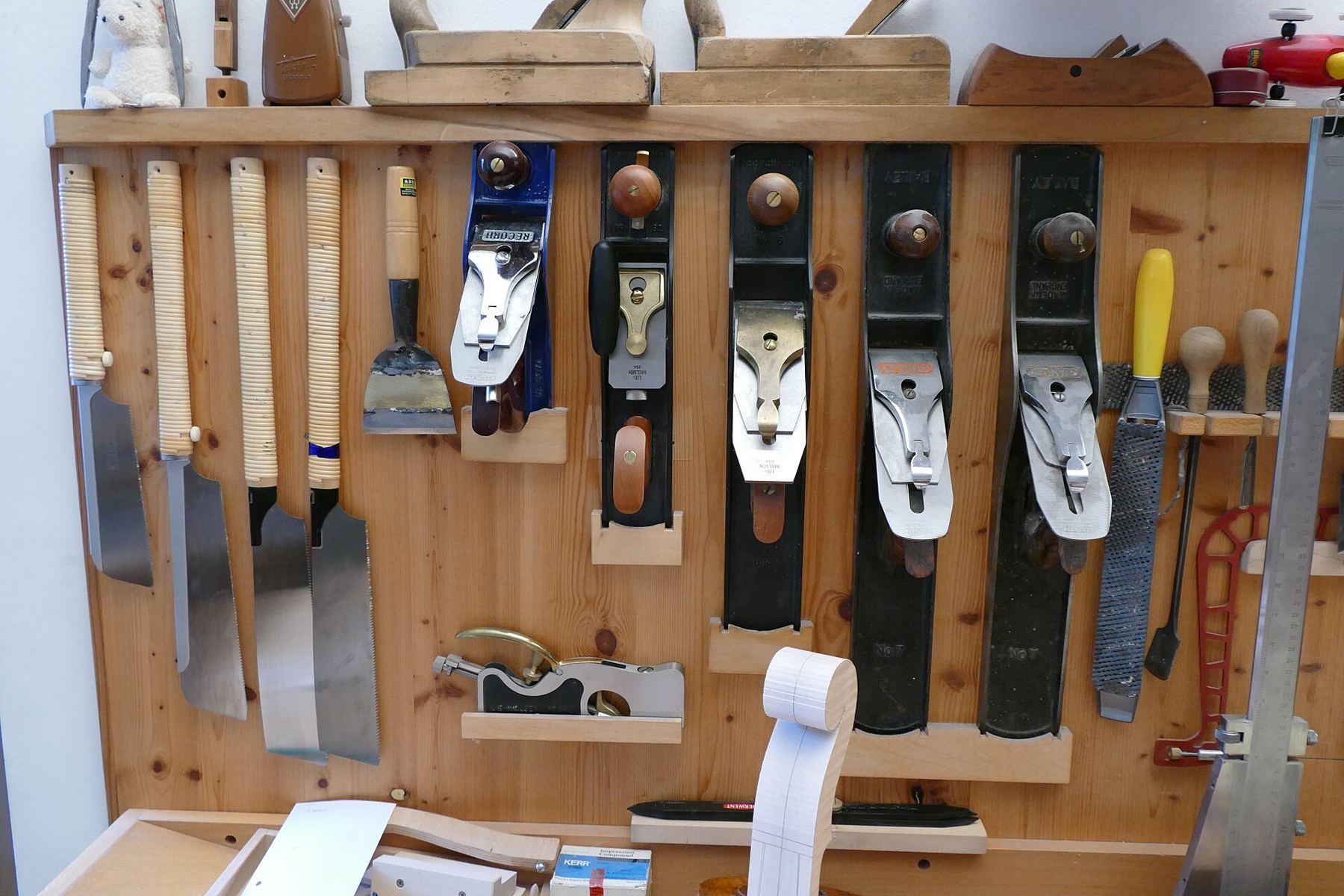 A wall-mounted rack of hand planes and woodworking tools
